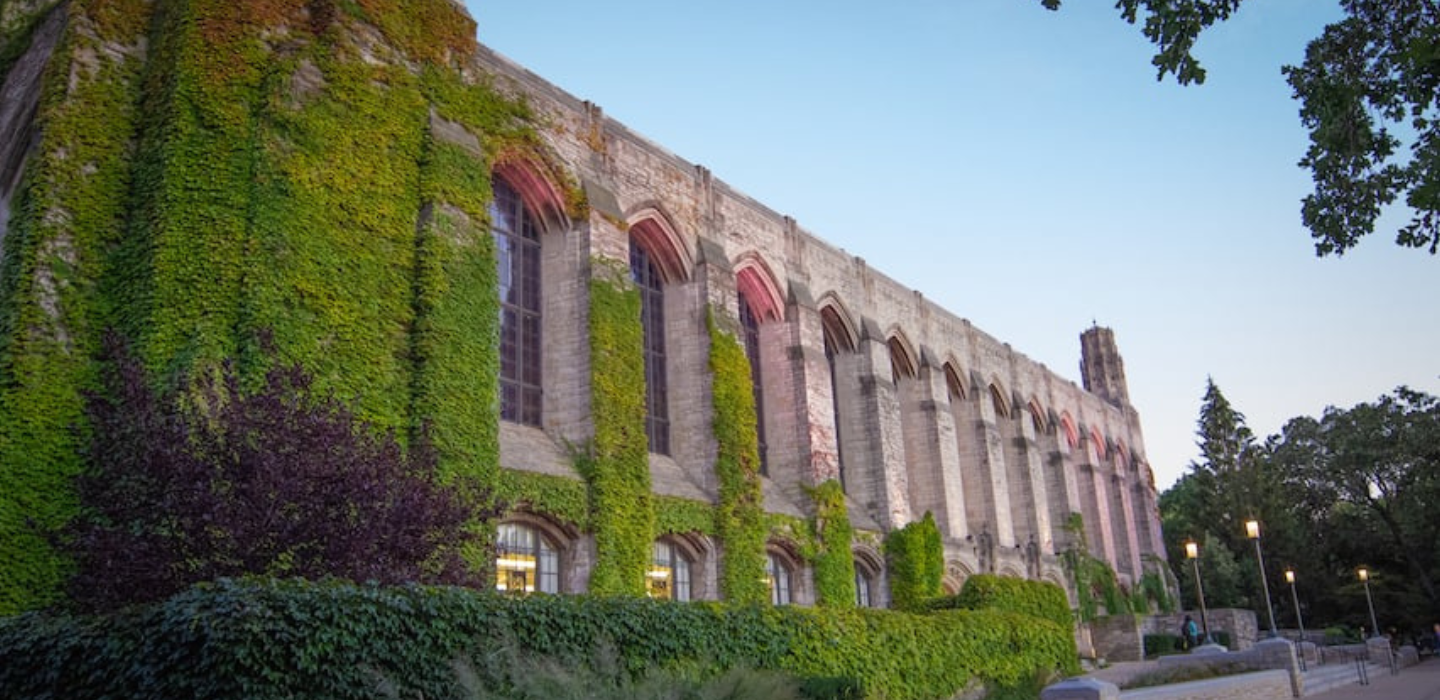 Photo of the west-facing, ivy-covered facade of Deering Library at dusk.