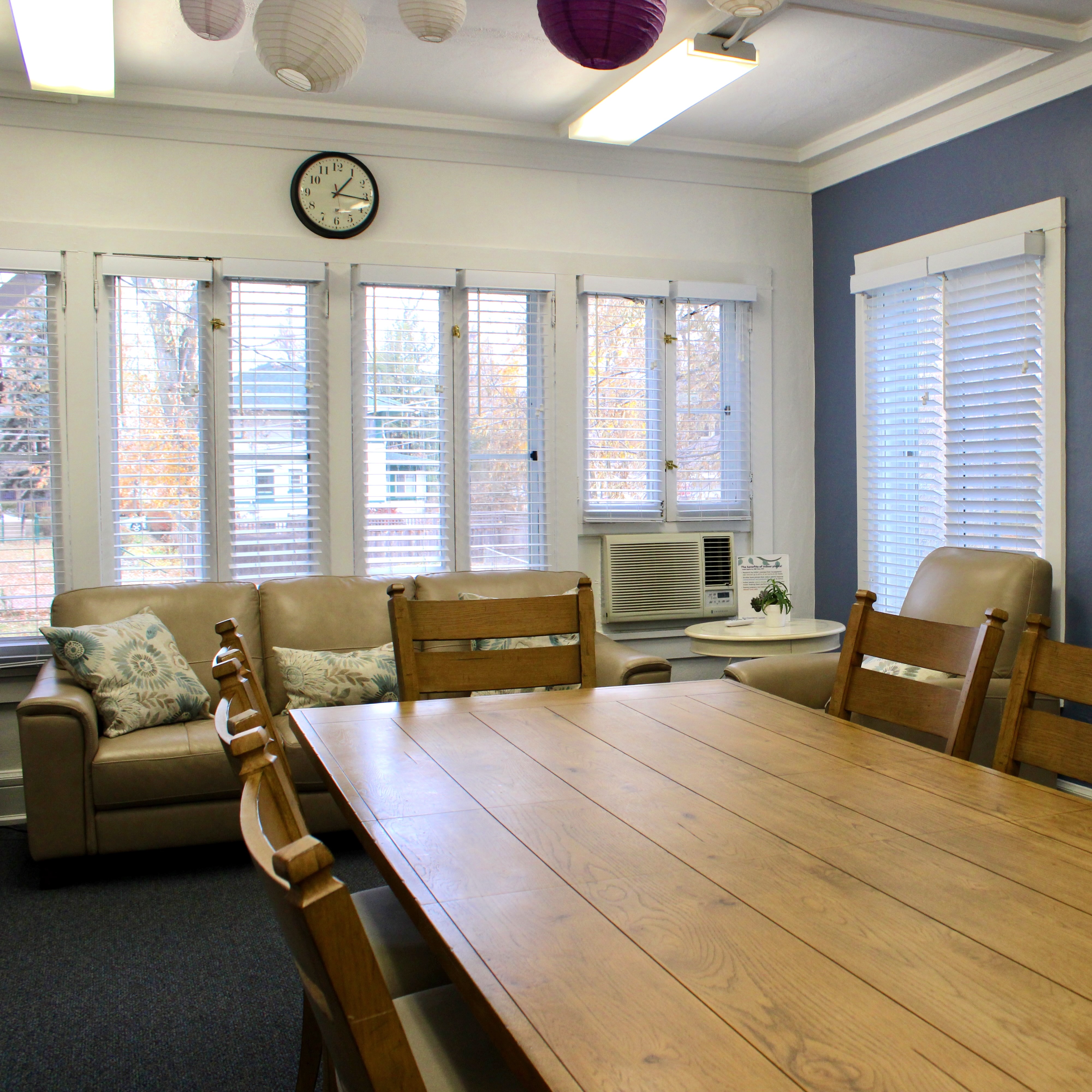 Photo of the Searle Center Meeting Room featuring a dining table, couch, and windows overlooking the Evanston campus.